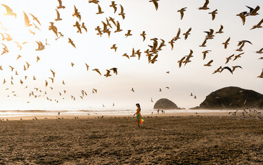 woman walking in the beach with birds flying