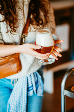 hand holding frothy beer glass in cozy, relaxed cafe setting