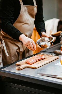 chef seasoning salmon fillet in vibrant kitchen setting.