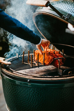 smoky barbecue grilling ribs in open bbq with wooden handles.