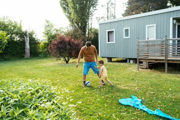 Father and son playing with ball in park in daylight