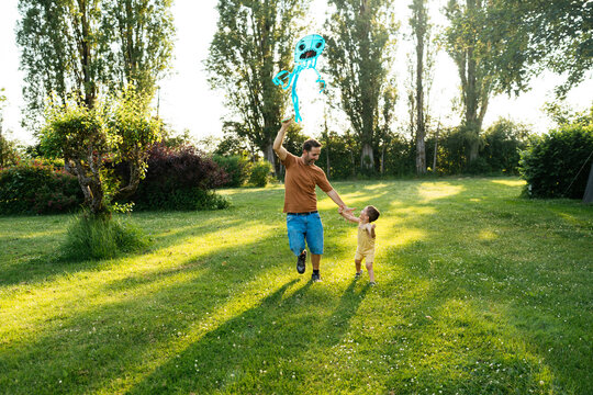 Happy man with little son launching kite in park