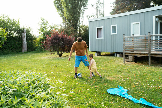Father and son playing with ball in park in daylight