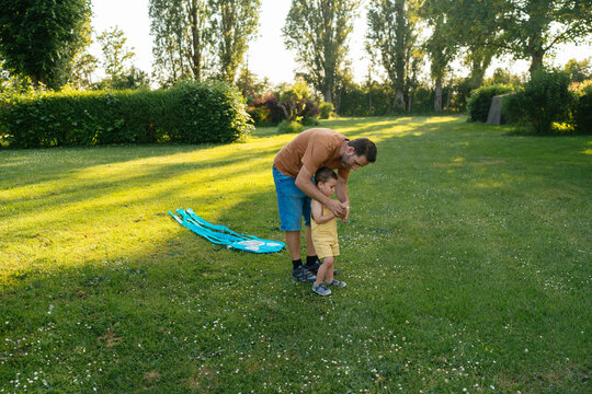Young dad with little song launching kite in park