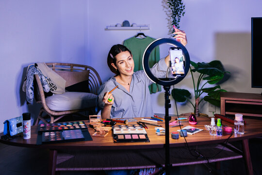 A person applies makeup while recording with a smartphone 