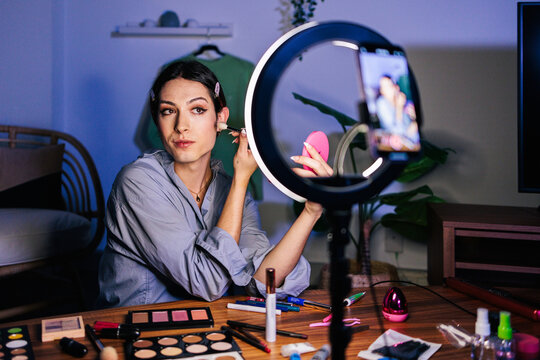 A person applying foundation while recording with a smartphone