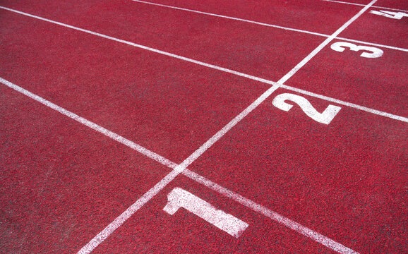 The red running track shows clear lane markings on a sunny day for athletes practice