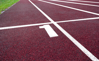 Red running track lane number one with clear white markings under bright sunlight