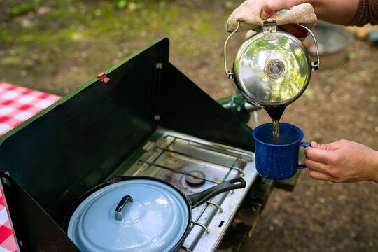 Pouring Coffee at a Campsite with Stove
