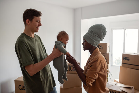 Happy couple playing with newborn while moving in