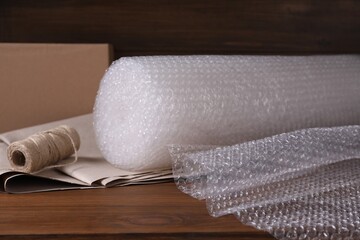 Twine, paper and roll of bubble wrap on wooden table