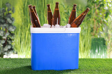 Wet beer bottles in cooler box on artificial grass
