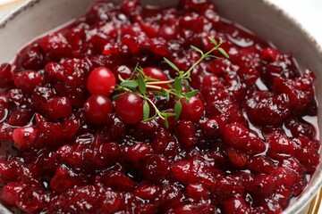 Tasty cranberry sauce and thyme in bowl, closeup