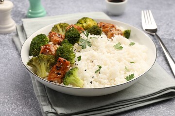 Tasty rice with broccoli and chicken served on grey table, closeup