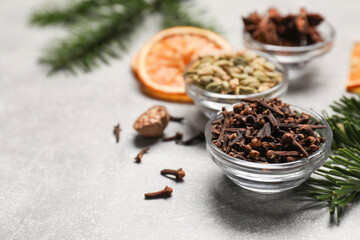 Different spices, dried orange slices and fir tree branches on light grey table, closeup. Christmas season