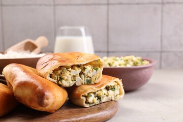 Delicious pirozhki (stuffed pastry pies) and ingredients on grey table, closeup. Space for text