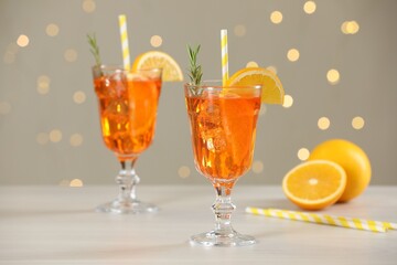 Tasty Christmas cocktail in glasses on white wooden table against blurred lights