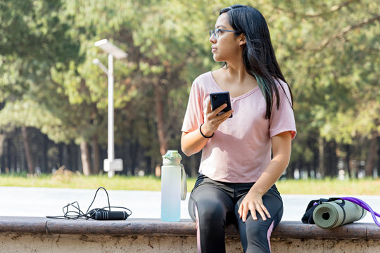 Sporty amteur enjoys a sunny morning while using a phone at the park