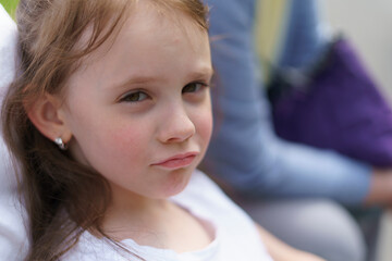 Beautiful cheerful girl in a white T-shirt having fun in the summer outdoors. Concept of an active, mobile, sincere child