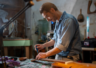 Guitar craftsman working on instrument detail in traditional workshop - artisan expertise