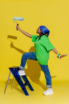 Woman on ladder holding paint roller, ready for home renovation