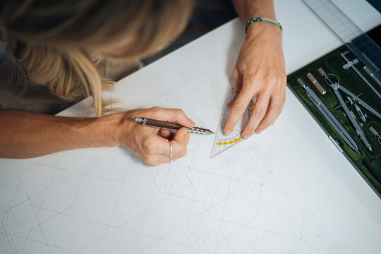 Artist using ruler and protractor creating geometric pattern