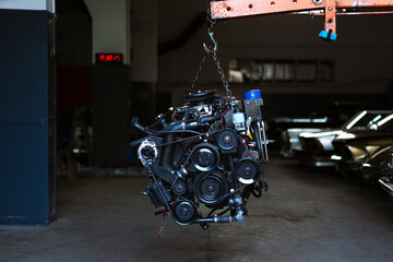 Automobile motor hanging on a crane in a garage