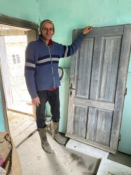 Tall worker stands next to a door.