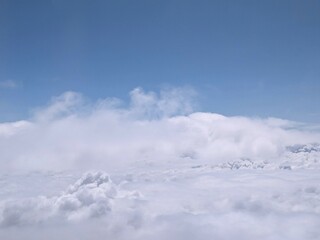 A white cloud is in the blue sky from an airplane window. Sky background
