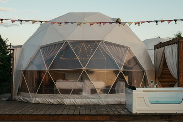 Unique geodesic dome accommodation with outdoor hot tub at sunset