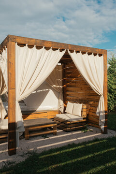 Cozy wooden gazebo with curtains in a serene outdoor setting