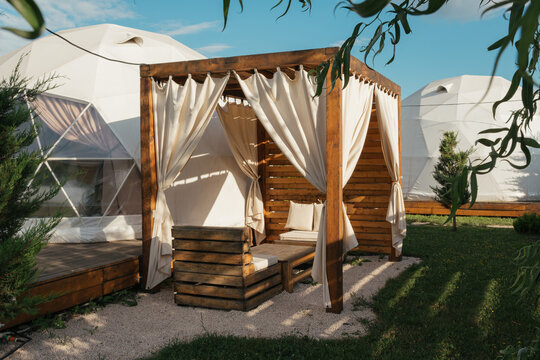 Cozy wooden gazebo with curtains in a serene outdoor setting