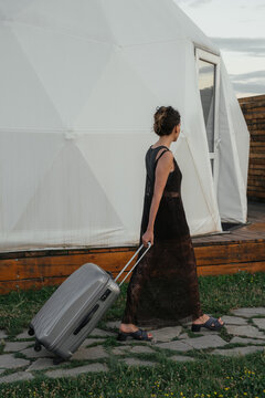 A traveler walking towards a geodesic dome with a suitcase in hand