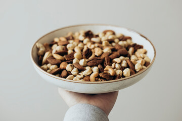 Assorted Nut Mix in Ceramic Bowl Held by a Hand