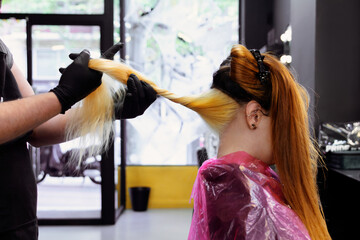 Hair stylist applying color highlights in modern salon