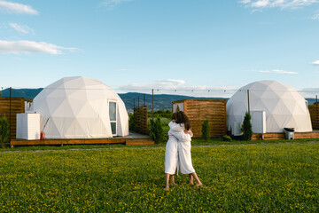 Two women stand in front of a geodesic dome