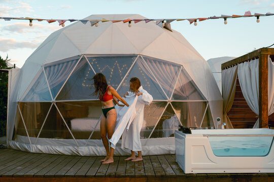 Two women relax in a white dome tent