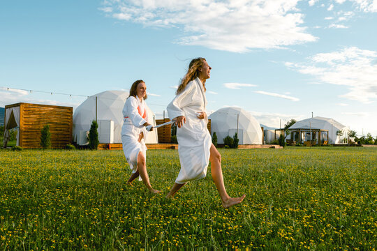 Friends playfully enjoying a sunny day in bathrobes in a field