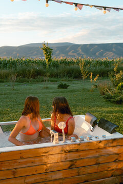 Two women relax in a hot tub with a view of the mountains