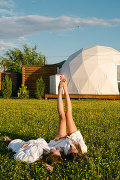 Two women relax in a field near glamping hotel