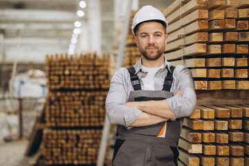 Carpenter smiling with crossed arms in lumber warehouse for modular building