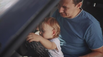 dad plays with his son in the car. people family and children concept. beautiful little kid sit and plays on his father's lap and turn the steering wheel of lifestyle his car - Powered by Adobe