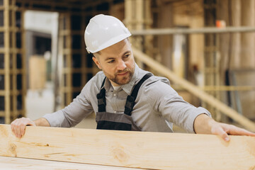 Carpenter working with wood plank in workshop for modular building