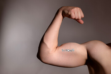 Arm flexing with strong text emphasizes health and fitness