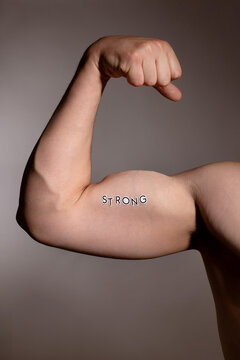 Muscular Arm Flexing with Strong Written on Bicep