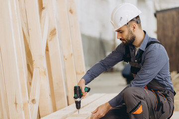 Carpenter using cordless drill assembling modular house wooden frame