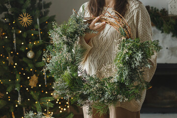 Christmas rustic wreath. Woman in sweater holding stylish christmas wreath wreath on on background...