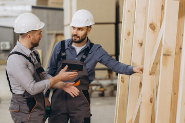 Construction workers discussing building wooden frame in workshop