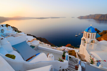 street of traditional greek village Oia of Santorini, with blue domes against Aegan sea and...