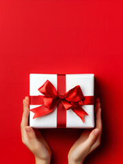 white gift with red ribbon in hands of girl 